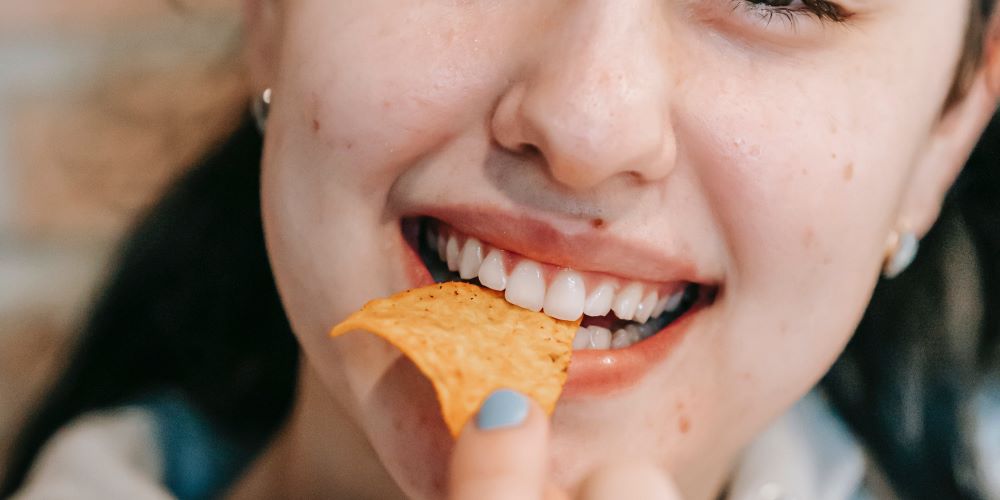 Frau isst Chips während Heisshungerattacke wegen erhöhtem Blutzuckerspiegel
