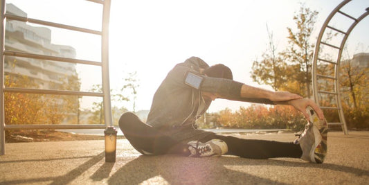 Sportler stretcht am Boden im Outdoor-Fitnesspark