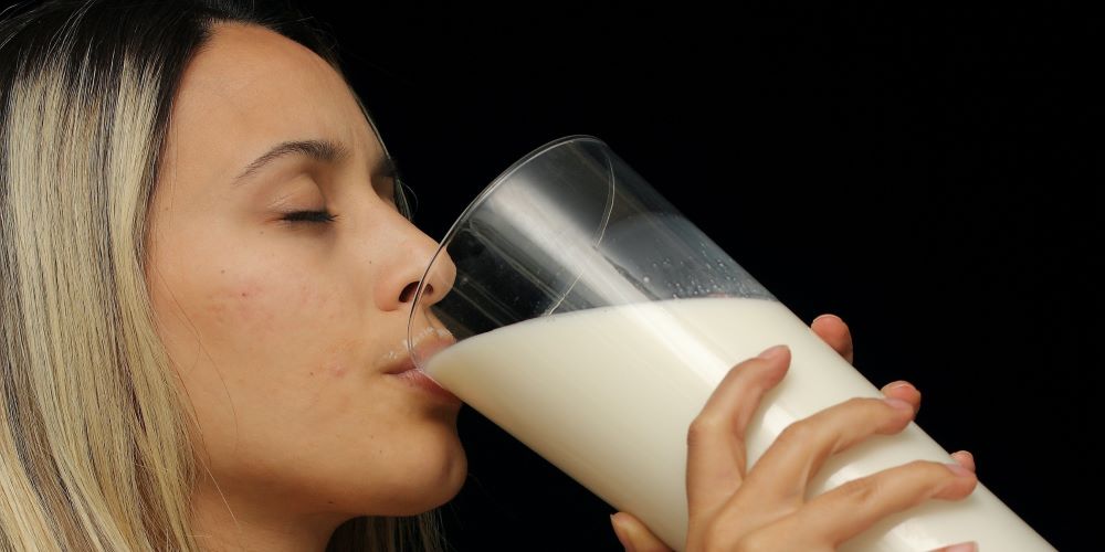 Frau trinkt aus einem grossen Glas Milch