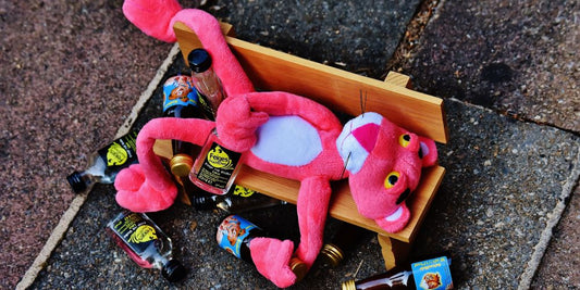 Betrunkener Plüsch-Pink-Panther auf Bank liegend