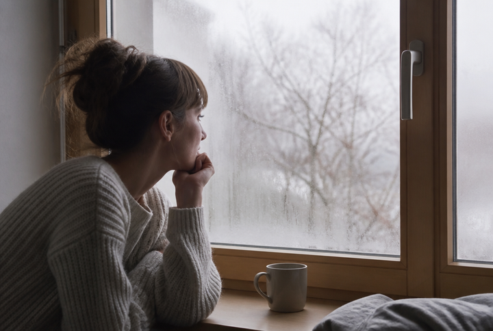 Beschlagenes Winterfenster mit einer Tasse auf der Fensterbank