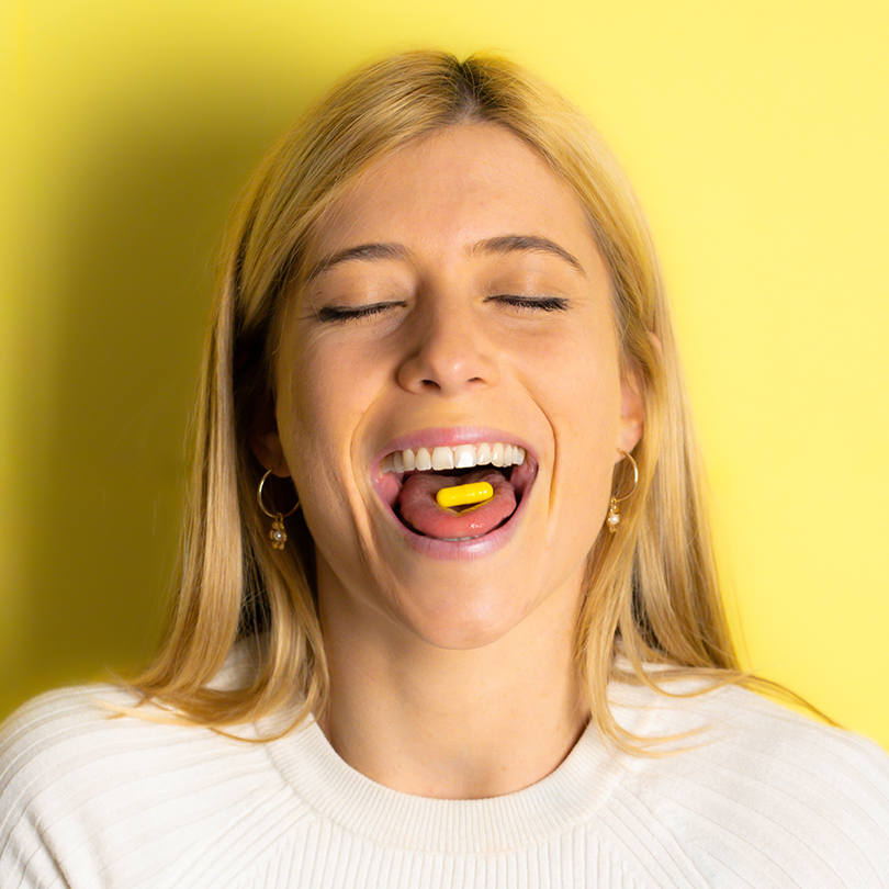 Frau mit gelber Kapsel im Mund