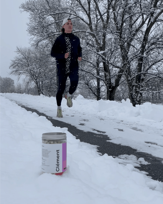 indyvit steht am Boden im Schnee, Läufer im Hintergrund